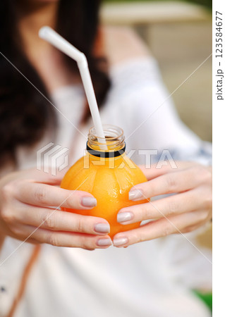 Closed up Asian woman hand holding fresh orange juice in bottle at outdoor in natural sunlight 123584677