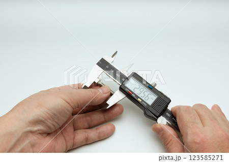 両手でデジタルノギス使ってボルトの長さを測る 123585271