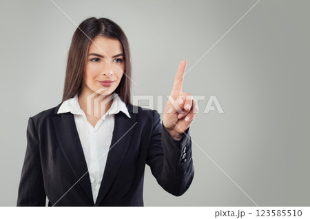 Positive business woman in black suit pointing finger up or pushing button on white background 123585510