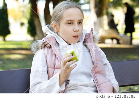 Funny kid holding green apple. Young girl in park, outdoors portrait Funny kid holding green apple. Young girl in park, outdoors portrait 123585583