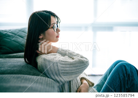ソファでくつろぎながら首に手を当てる女性 123585794
