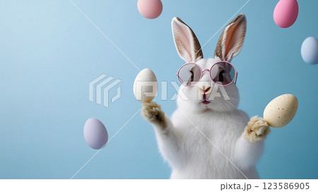 Fashionable White Bunny Juggling Easter Eggs on Blue Background for Happy Easter Concept 123586905