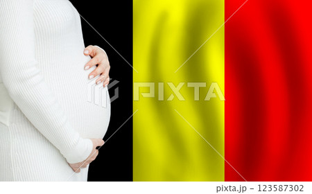 Pregnant woman belly against Belgian flag background. Demographics and pregnancy in Belgium concept 123587302
