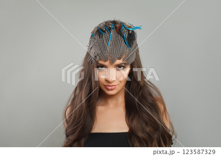 Glam female model with healthy long wavy hairstyle, trendy make-up and hairdeco feathers accessories Glam female model with healthy long wavy hairstyle, trendy make-up and hairdeco feathers accessories 123587329
