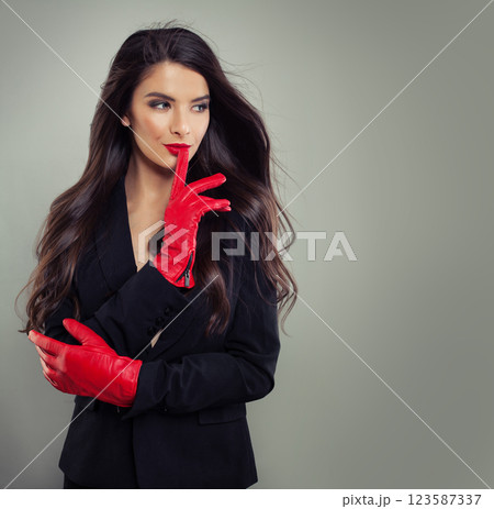 Cheerful fashionable woman with make-up and dark hair wearing red leather gloves and black suit 123587337