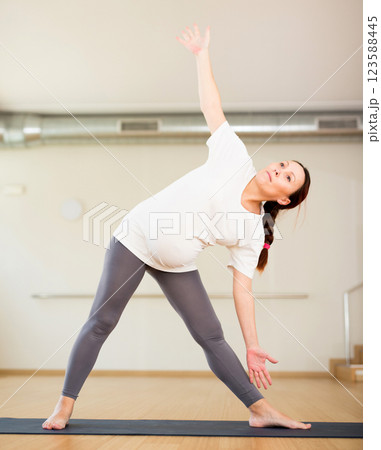 Pregnant woman is engaged in yoga. Elongated Triangle Pose or Utthita Trikonasana 123588445