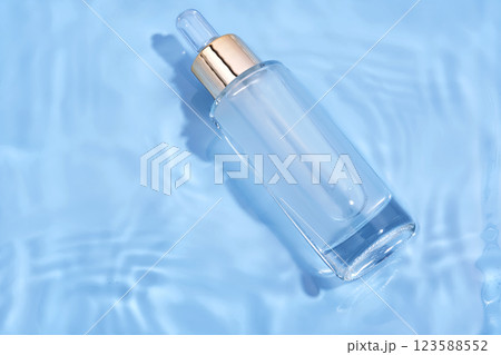 Bottle with moisturizing serum in water on blue background. 123588552