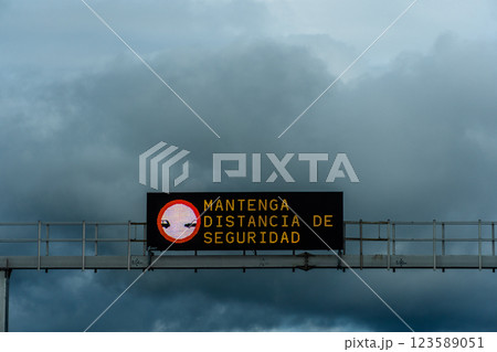 The road sign in Spanish reminds drivers to keep a safe distance on a cloudy day. 123589051
