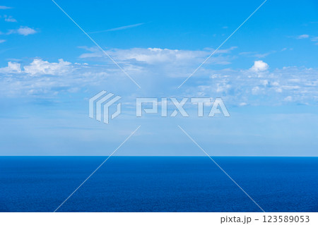 Vast expanse of the deep blue ocean meeting a bright sky with fluffy white clouds. Vast expanse of the deep blue ocean meeting a bright sky with fluffy white clouds. 123589053