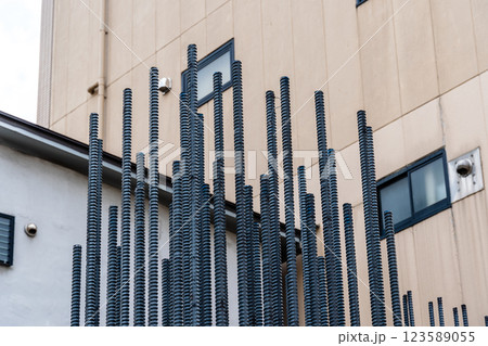 Bundles of vertically stacked rebar protrude against the side of a building construction site. 123589055