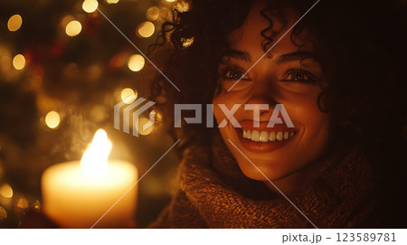 Woman holds a candle, smiling warmly with blurred lights in the background. Concept: warmth, joy, celebration. 123589781