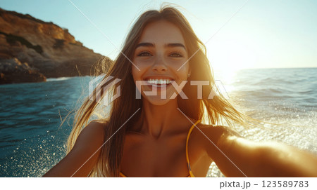 Smiling woman takes a selfie near the sea during sunset with cliffs in the background. Concept of happiness and travel. 123589783