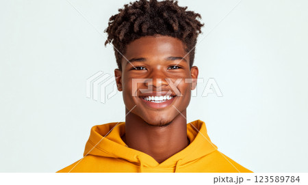 Smiling person wearing a yellow hoodie against a light background. Concept of happiness and youth. 123589784