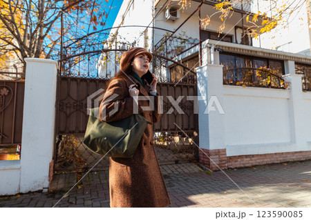 Mid shot of a Caucasian beautiful young woman in a coat and beret, calling on a smartphone on the street. Bottom view. City lifestyle 123590085
