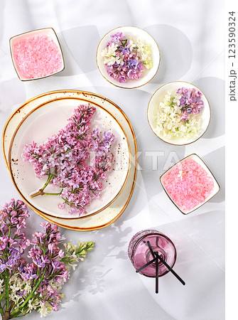 Advertising postcard of spa salon. Wellness composition with lilac water, pink salt, aromatic sticks and fresh lilac flowers, Concept of natural self-care and healthy lifestyle, abstract composition Advertising postcard of spa salon. Wellness composition with lilac water, pink salt, aromatic sticks and fresh lilac flowers, Concept of natural self-care and healthy lifestyle, abstract composition 123590324