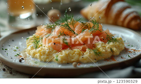 On a fine china plate, creamy scrambled eggs are garnished with smoked salmon flakes, fresh dill, and a dollop of creme fraiche 123590329