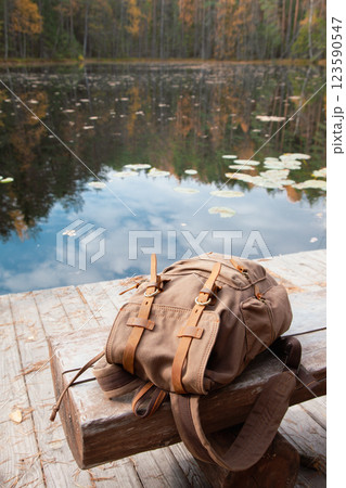 Backpack of traveller on wooden pier on blue lake. 123590547