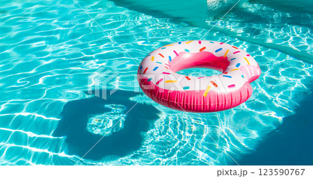 Pink donut inflatable float in turquoise swimming pool with sunlight reflections and shadow Pink donut inflatable float in turquoise swimming pool with sunlight reflections and shadow 123590767