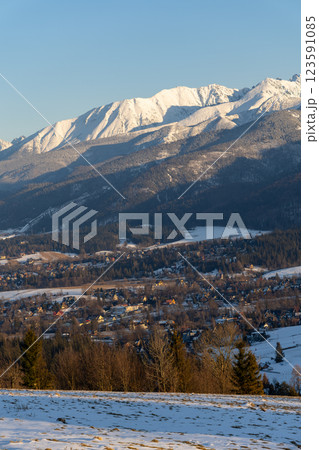 Stunning winter landscape of Zakopane, Poland, featuring the snow-covered Tatra Mountains at sunset. The picturesque alpine town, surrounded by forests and peaks, offers breathtaking views and is a po 123591085
