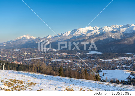Stunning winter landscape of Zakopane, Poland, featuring the snow-covered Tatra Mountains at sunset. The picturesque alpine town, surrounded by forests and peaks, offers breathtaking views and is a po Stunning winter landscape of Zakopane, Poland, featuring the snow-covered Tatra Mountains at sunset. The picturesque alpine town, surrounded by forests and peaks, offers breathtaking views and is a po 123591086