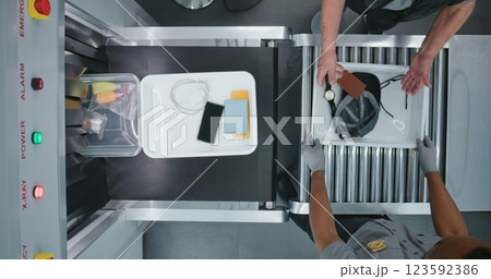 Diverse People, Travelers Putting Personal Items in Plastic Trays for X-ray Scanning on Conveyor Belt 123592386