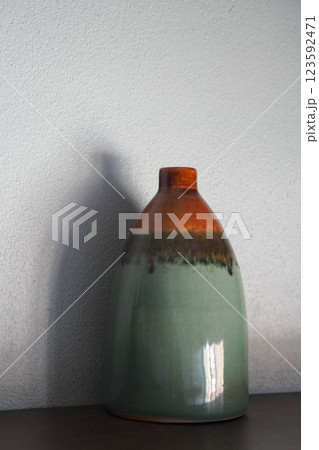 beautiful gradient orange and black and green ceramic vase on brown wooden floor, white wall background, object, decor, fashion, ancient, copy space 123592471