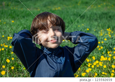 Close up portrait joyful child with closed eyes relaxing in sunny field with yellow flowers 123592659