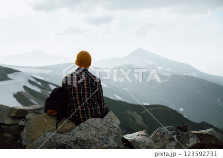 A tourist sits on the stones on the edge of a mountain 123592731