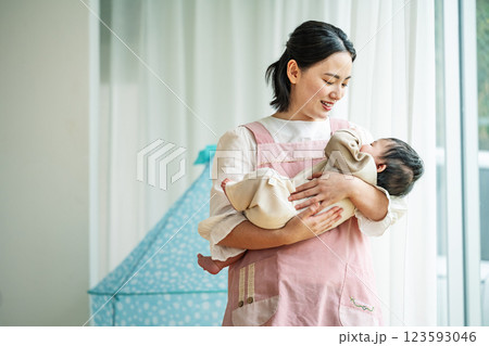 0歳児の赤ちゃんを抱っこする女性の保育士 123593046