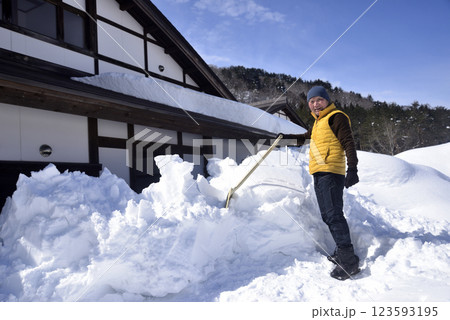 屋根の雪下ろしと排雪をしている老人 屋根の雪下ろしと排雪をしている老人 123593195