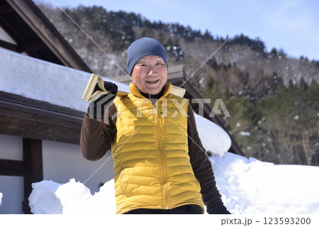 屋根の雪下ろしと排雪をしている老人 123593200