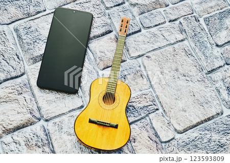 Yellow acoustic guitar,phone with space for text,on a cobbled background Yellow acoustic guitar,phone with space for text,on a cobbled background 123593809