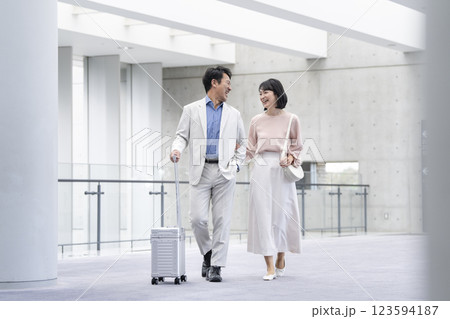 キャリーバッグを持って歩く笑顔の50代の夫婦  キャリーバッグを持って歩く笑顔の50代の夫婦  123594187