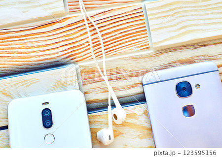 Two mobile phones with headphones on wooden surface 123595156