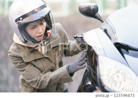 バイクの車体を見て驚く女性 123596873
