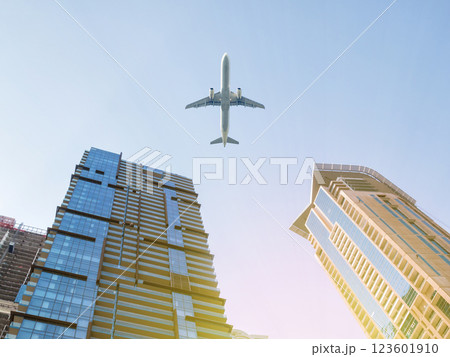 Skyscraper facades on a bright sunny day with sunbeams in the blue sky and passenger aircraft flying over it Skyscraper facades on a bright sunny day with sunbeams in the blue sky and passenger aircraft flying over it 123601910