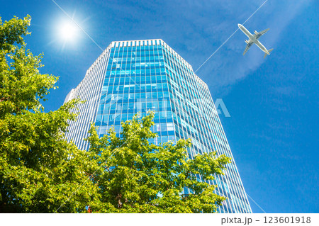 A modern office skyscraper and white passenger aircraft flying over this building 123601918
