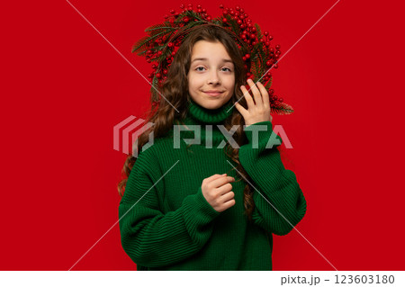 Teen girl wearing green sweater and Christmas berry wreath Teen girl wearing green sweater and Christmas berry wreath 123603180