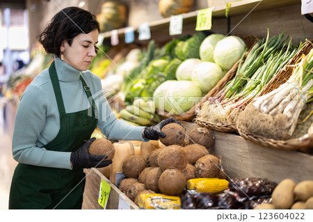 Adult woman seller puts coconuts on display Adult woman seller puts coconuts on display 123604022