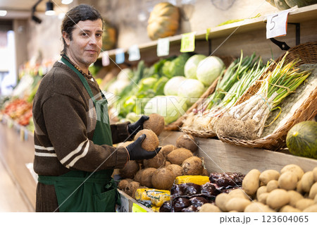 Man shop seller puts cocoanut goods on display case Man shop seller puts cocoanut goods on display case 123604065