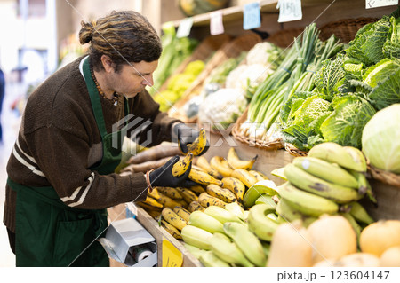 Adult man seller puts bananas on display 123604147
