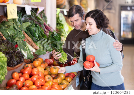 Married couple selects fresh bell peppers, tomatoes and other vegetables at supermarket counter Married couple selects fresh bell peppers, tomatoes and other vegetables at supermarket counter 123604285