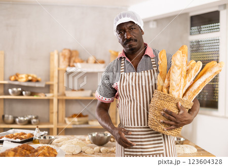Successful African baker presenting golden baguettes in bakery Successful African baker presenting golden baguettes in bakery 123604328