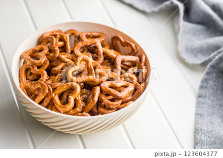 Heart shaped pretzel in bowl on white table. Heart shaped pretzel in bowl on white table. 123604377