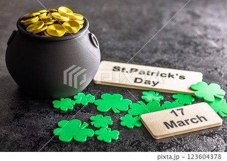 St. Patrick's Day. Green clover leaves decoration and cauldron with golden coins on black table. St. Patrick's Day. Green clover leaves decoration and cauldron with golden coins on black table. 123604378
