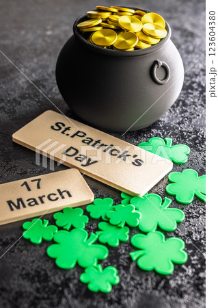 St. Patrick's Day. Green clover leaves decoration and cauldron with golden coins on black table. St. Patrick's Day. Green clover leaves decoration and cauldron with golden coins on black table. 123604380