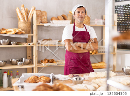 Caucasian man cook-baker stands at table in kitchen of bakery 123604596
