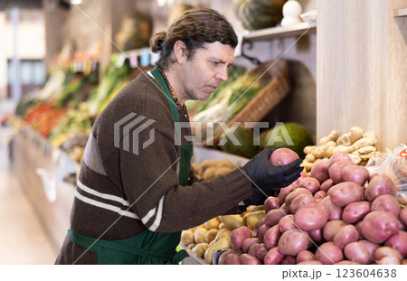Man shop seller puts potato goods on display case Man shop seller puts potato goods on display case 123604638
