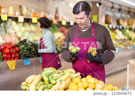 Man shop seller puts banana goods on display case 123604673