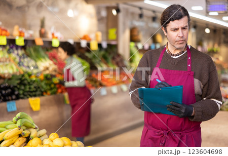 Man store employee with folder of documents takes inventory in vegetable store 123604698
